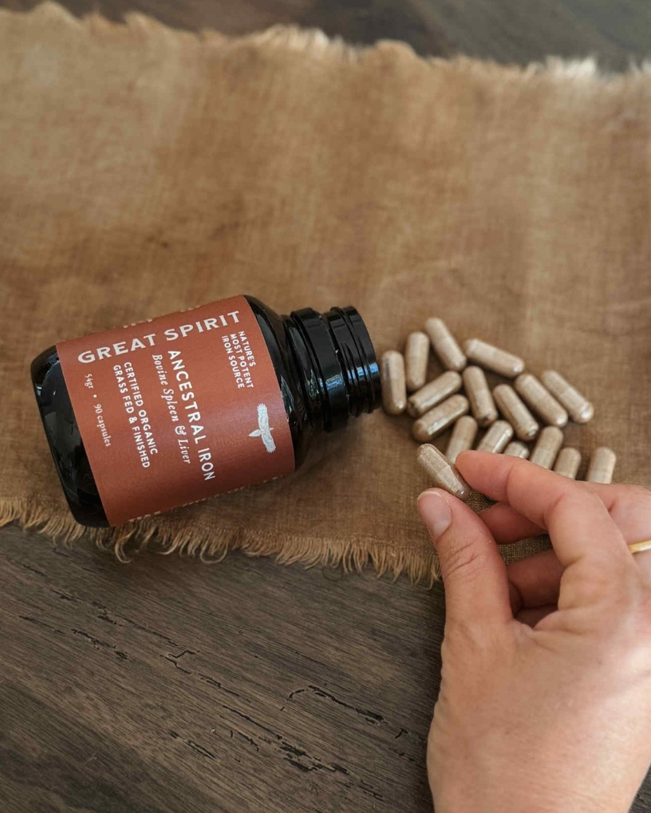 Bottle of 'Great Spirit' with capsules on a wooden surface