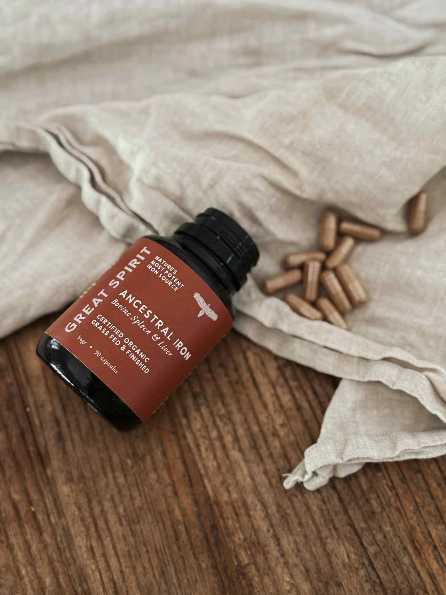 Bottle of 'Great Spirit' with capsules on a wooden surface